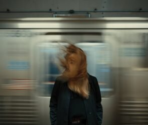 panning photography of train with woman standing in front